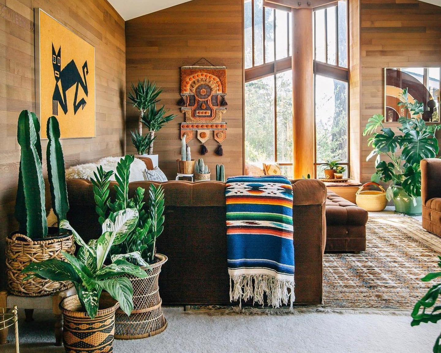 Living room with wooden walls, large windows, and decorative elements.